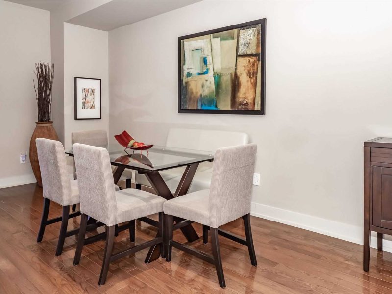 A dining room table with chairs and a painting on the wall.