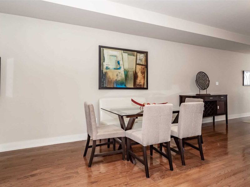 A dining room table with chairs and a painting on the wall.